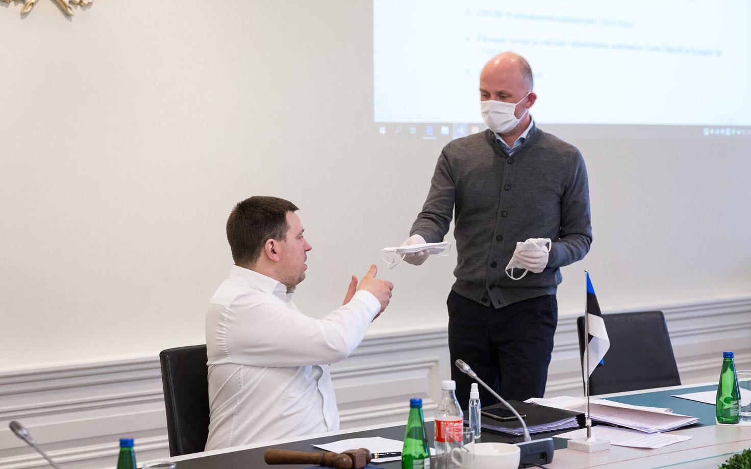 Госсекретарь Таймар Петеркоп дает маску премьер-министру Юри Ратасу перед заседанием правительства 6 апреля.