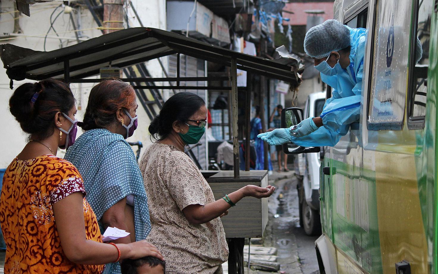 Meditsiinitöötaja väljastab India naistele koroonaviiruse vastaseid ravimeid.
