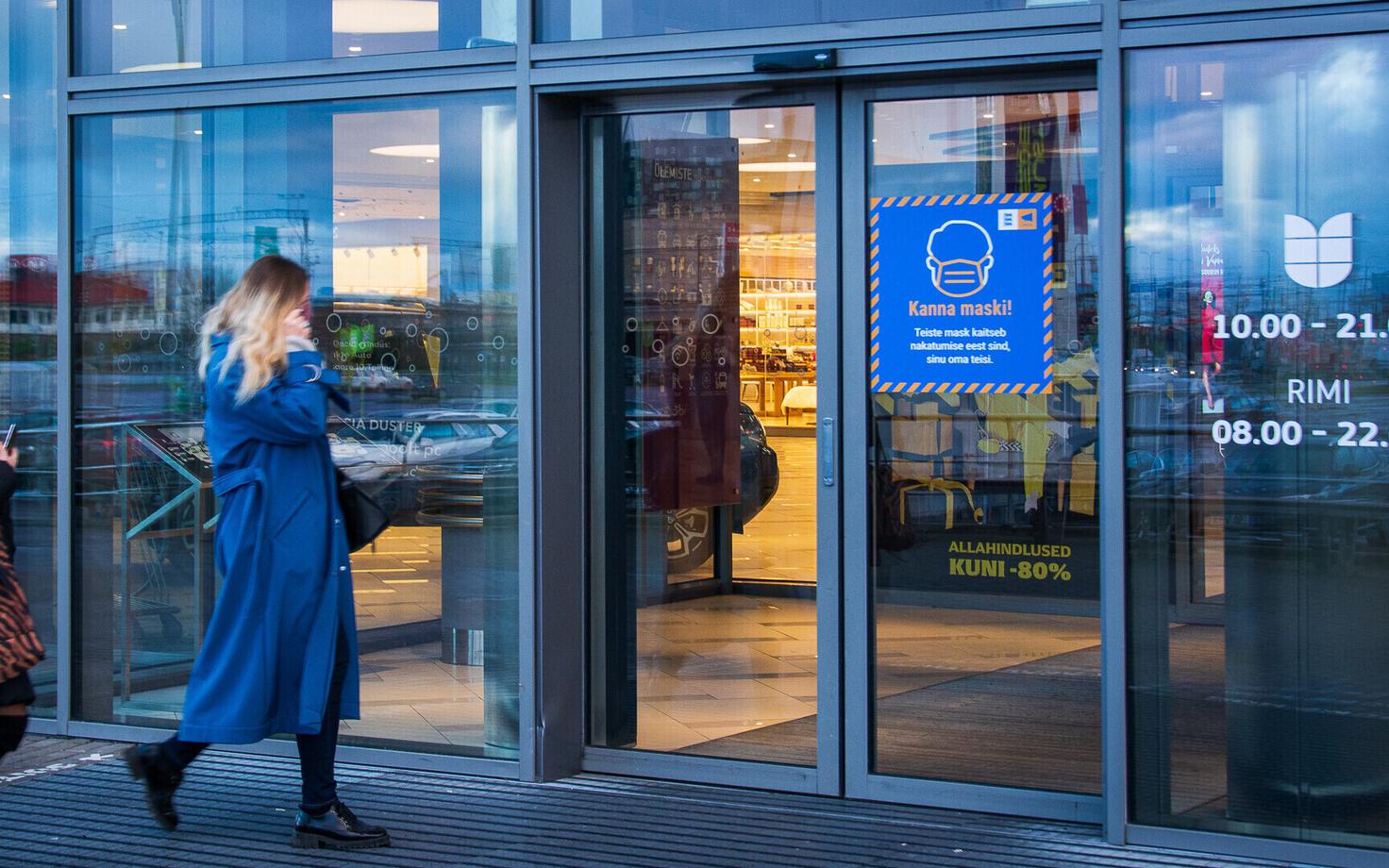 A government sign urging people to wear a mask on a shopping center door.