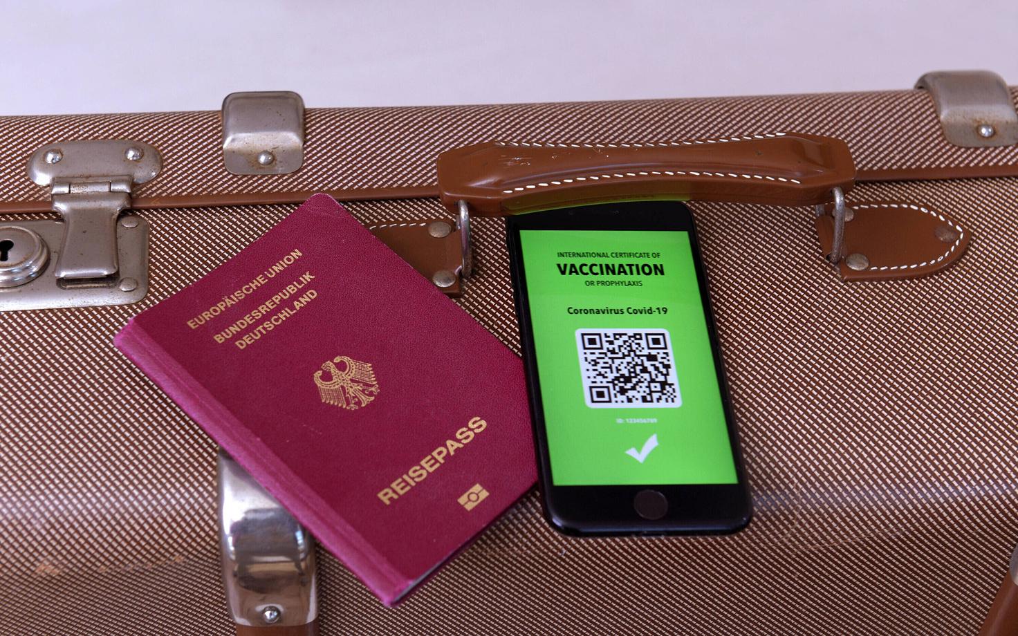 Kohver koos passi ja vaktsineerimise QR-tõendiga.
