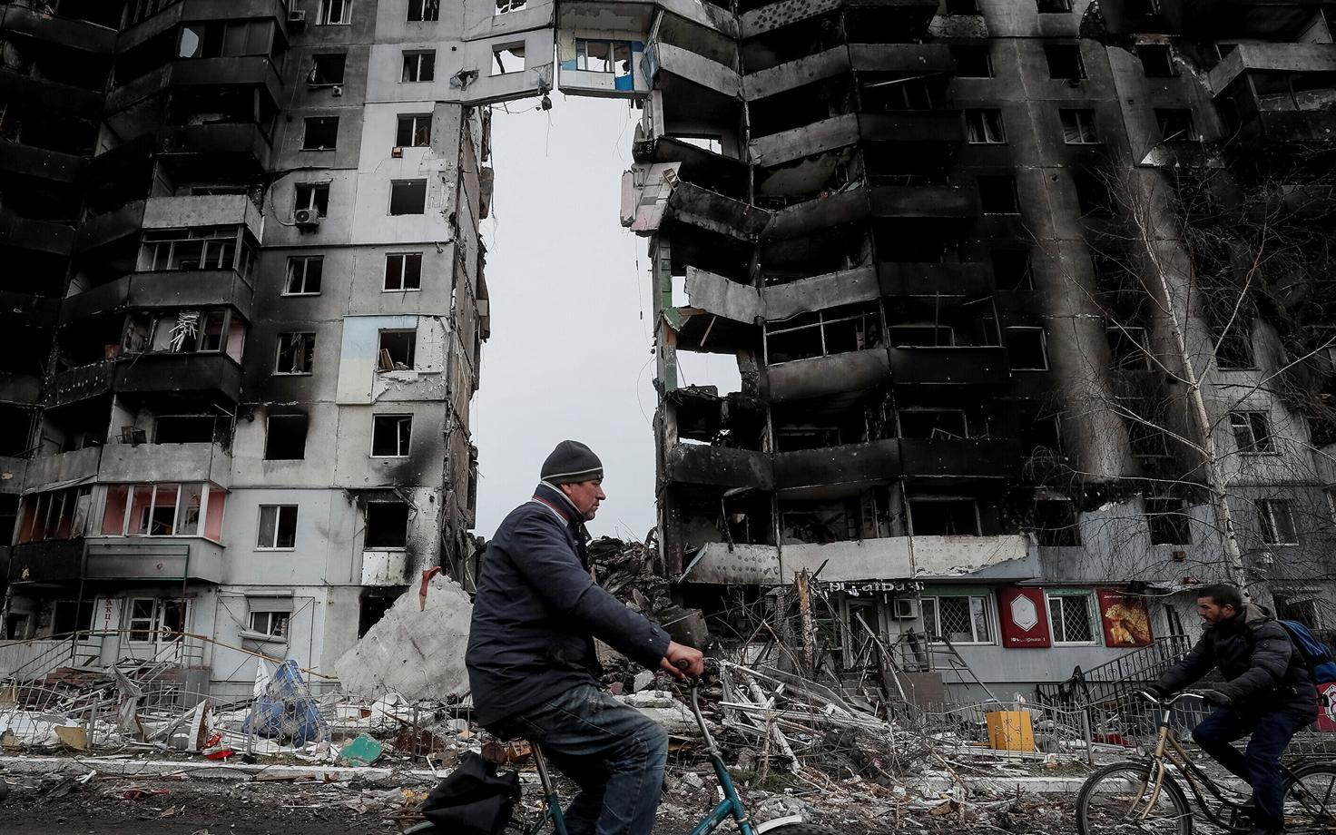 Жители Бородянки передвигаются между разрушенными домами.