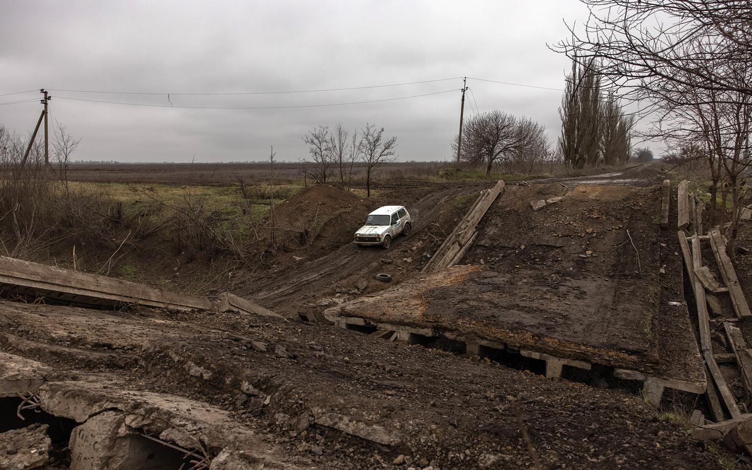 Инфраструктура Украины сильно пострадала из-за развязанной Россией войны, на снимке машина проезжает по разрушенному мосту около Херсона.
