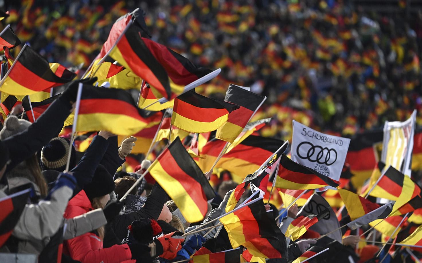 Немецкие спортивные болельщики наблюдают за соревнованиями по прыжкам с трамплина.