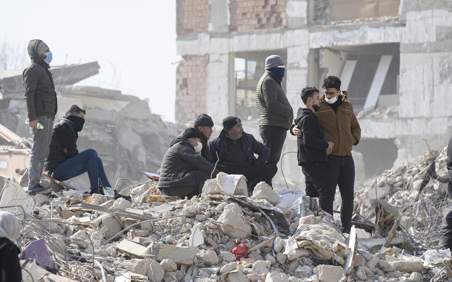 Пережившие землетрясение на руинах в Кахраманмараше, Турция.