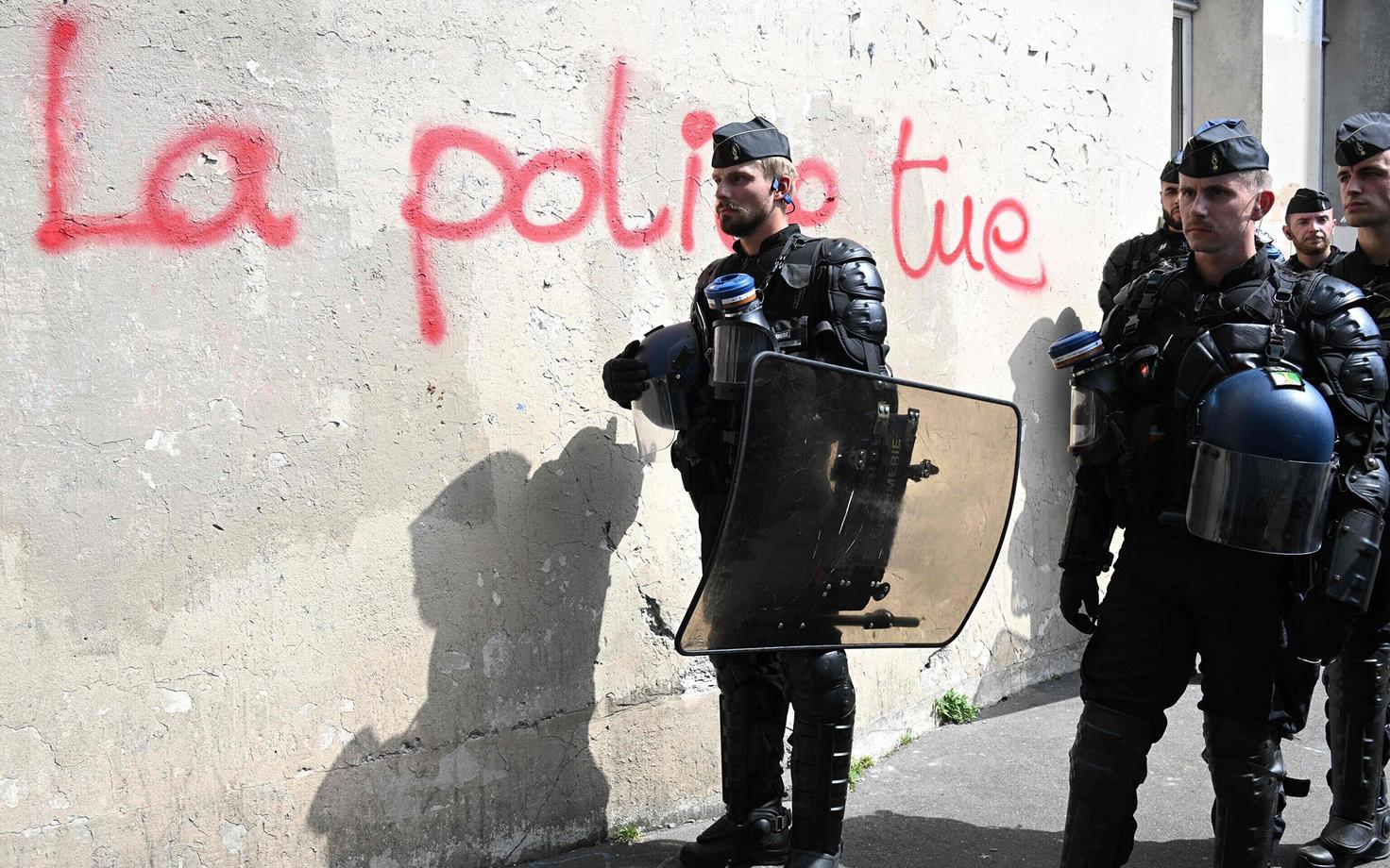 Французские жандармы стоят у стены с надписью